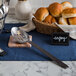 A basket of rolls and an American Metalcraft wavy aged stainless steel slotted spoon.