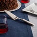 An American Metalcraft stainless steel pie server with a chocolate cake on a table with a knife and fork.