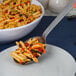 An American Metalcraft hammered stainless steel slotted spoon serving pasta with vegetables.