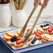American Metalcraft gold tongs serving fruit on a plate.