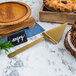 A pie and a gold hammered pie server on a marble table.