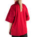 A woman wearing a Mercer Culinary Millennia Air red chef jacket with full mesh back.