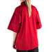 A woman wearing a Mercer Culinary Millennia Air red cook jacket with full mesh back.