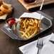 A Tablecraft stainless steel serving tray with french fries, onion rings, ketchup, and a fork.