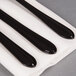 A group of black utensils on a white napkin with a black border.