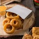 A Tablecraft stainless steel fry cup filled with fried onion rings and a side of sauce.