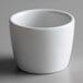 A Tuxton white porcelain sake cup on a gray surface.