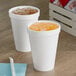 Two Dart white foam cups with drinks on a table.