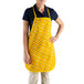 A woman wearing a yellow Funnel Cake bib apron with a flower design.