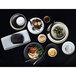 A table set with Tuxton TuxTrendz Zion matte black china bowls and plates of food.
