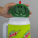 A hand holding a green lid over a green and white Mountain Dew Mini Tanker.