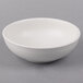 A Tuxton TuxTrendz white china bowl on a gray background.