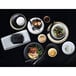 A table set with Tuxton Zion Matte Black China plates and white bowls of food.