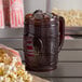 A translucent brown plastic barrel mug filled with a drink and popcorn.