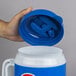 A hand holding a blue and white Pepsi Tanker with a lid and straw.