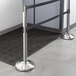 A Lancaster Table & Seating ADA compliant stanchion with dual retractable belts on silver poles.