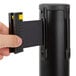 A hand using a Lancaster Table & Seating black crowd control stanchion with a clear cover.