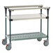 A grey and green metal Metro PrepMate cart with wheels and a shelf.