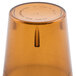 A close up of a Cambro amber plastic tumbler on a table.