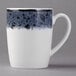 A white Schonwald stone porcelain coffee mug with a black and white speckled surface and white handle.