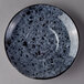 A white porcelain saucer with black and gray speckles.