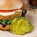 A burger with Harvest Fresh Dill Pickle Slices on a white background.