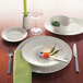 A table setting with a Schonwald white porcelain plate, fork, knife, and spoon.