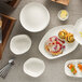 A stack of Schonwald bone white porcelain bowls on a table with food.