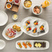 A table set with Schonwald bone white oblong porcelain platters of food and drinks.