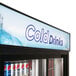 A Turbo Air black refrigerated sliding glass door merchandiser filled with soda cans.