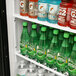 The open shelf of a Turbo Air refrigerated merchandiser with bottles of liquid and soda.