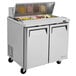 A stainless steel Turbo Air refrigerated sandwich prep table with food on it.