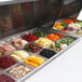 A Turbo Air refrigerated sandwich prep table with trays of food in a salad bar.