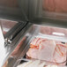 A tray of meat and vegetables in a Turbo Air refrigerated sandwich prep table.