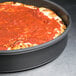 An American Metalcraft hard coat anodized aluminum deep dish pizza pan with a pizza in it.