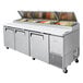 A Turbo Air 93" refrigerated pizza prep table with food in the trays.