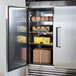 A Turbo Air reach-in refrigerator with its door open and food inside.