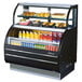 A black Turbo Air dual service refrigerated open display case with food and drinks inside.