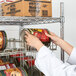 A person putting cans of food on a Regency chrome wire shelf with can racks.