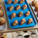 A blue Cambro market tray of pastries and muffins on a counter in a bakery display.