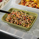 A G.E.T. Bugambilia willow green rectangular china bowl filled with pasta and vegetables on a salad bar counter.
