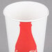 A white paper cup with a red Coca-Cola bottle design.