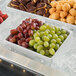 A G.E.T. Enterprises Bugambilia white rectangular salad bowl on a tray of grapes on ice.