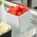 A G.E.T. Enterprises white resin-coated square salad bowl filled with cubed watermelon.