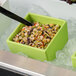 A lime green G.E.T. Enterprises Bugambilia resin-coated aluminum square salad bowl filled with food with a spoon in it.
