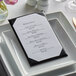 An Oakmont menu cover on a table with a plate and silverware.