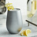 A Stolzle silver stemless wine glass with a lemon twist on top.