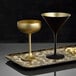 Two Stolzle gold coupe glasses on a tray.