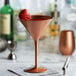 A Stolzle copper martini glass with a strawberry on top.