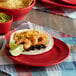 A Tuxton Concentrix cayenne plate with shrimp tacos, black beans, and guacamole.